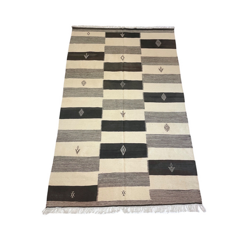 black and white alternating bands on large flatweave Moroccan rug in white, grey, and black, embellished by embroidered designs