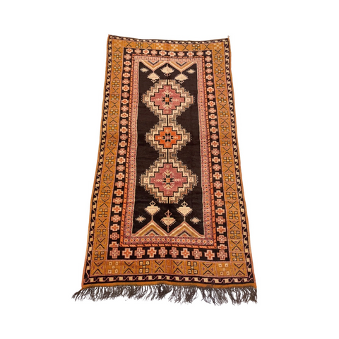 vintage low pile moroccan rug with orange border and geometric designs with three diamonds that form the central medallion