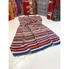 Multicolored striped fabric on a white floor with patterned rugs in the background