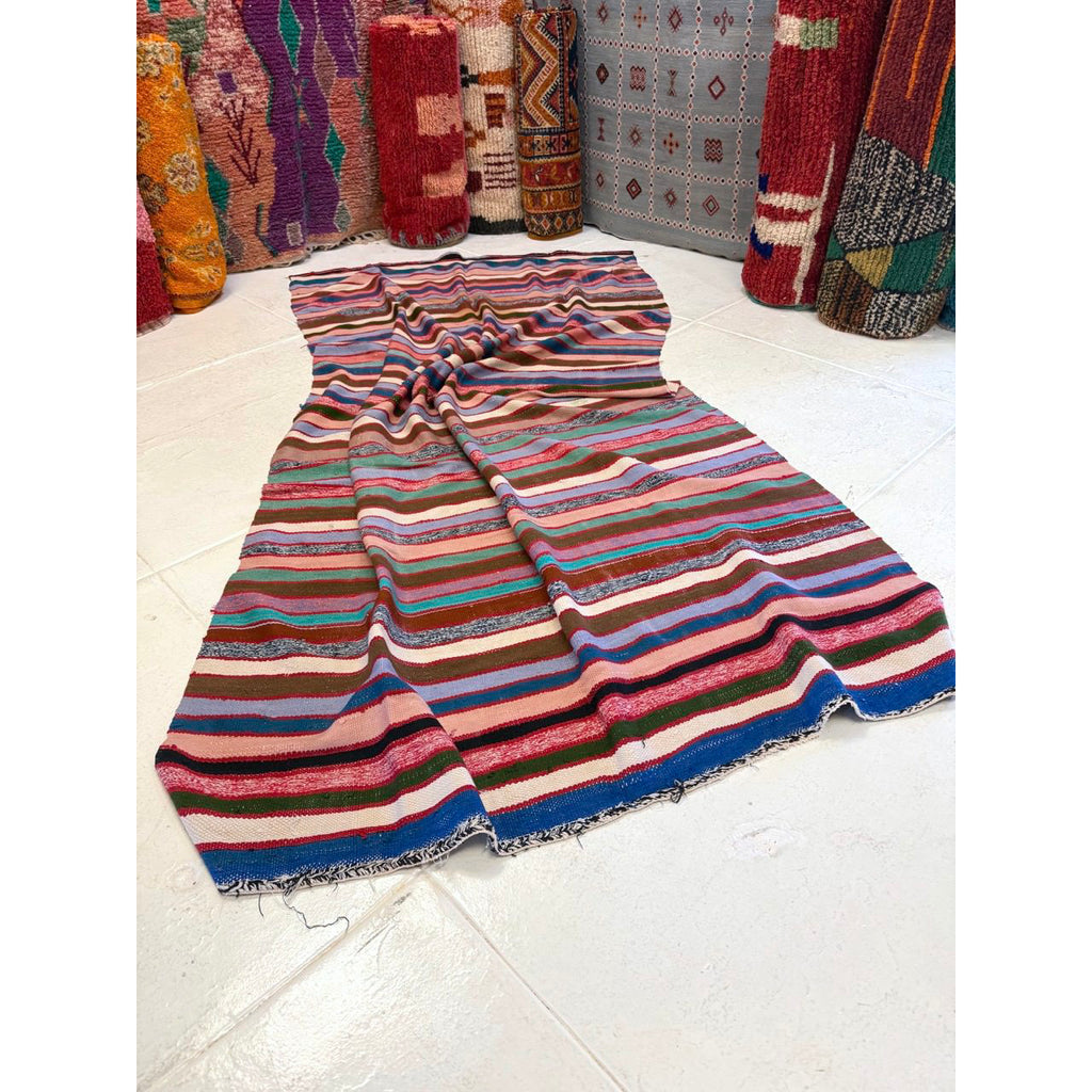 Multicolored striped fabric on a white floor with patterned rugs in the background