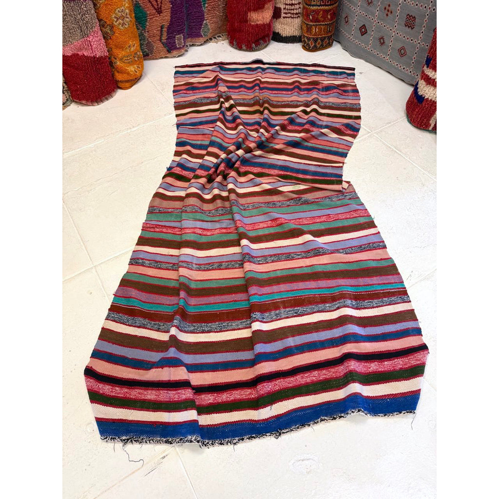 Striped Moroccan blanket crumpled up on a white floor