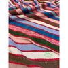Close-up of multicolored striped vintage Moroccan blanket with a small green emblem.