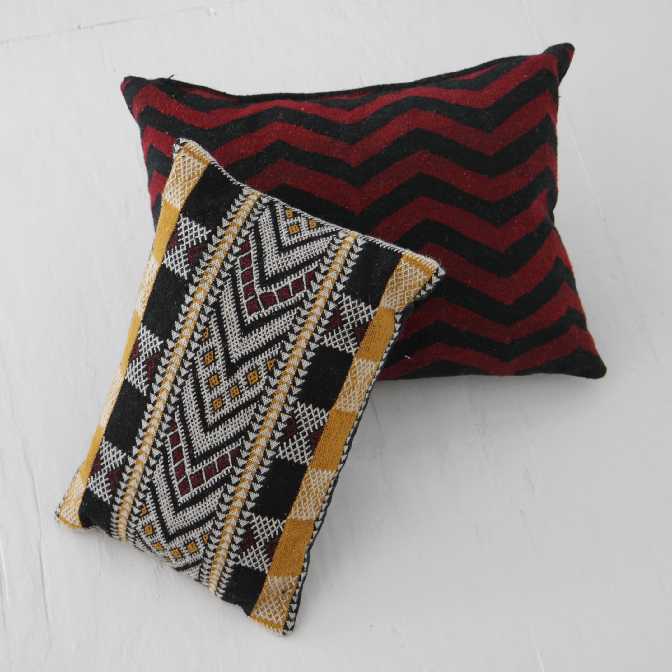 Black and mustard Moroccan pillow paired with simple geometric pillow in red and black zig zag pattern