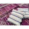 Two colorful Moroccan handira wedding blanket pillows on top of an abstract purple Moroccan rug from Kantara