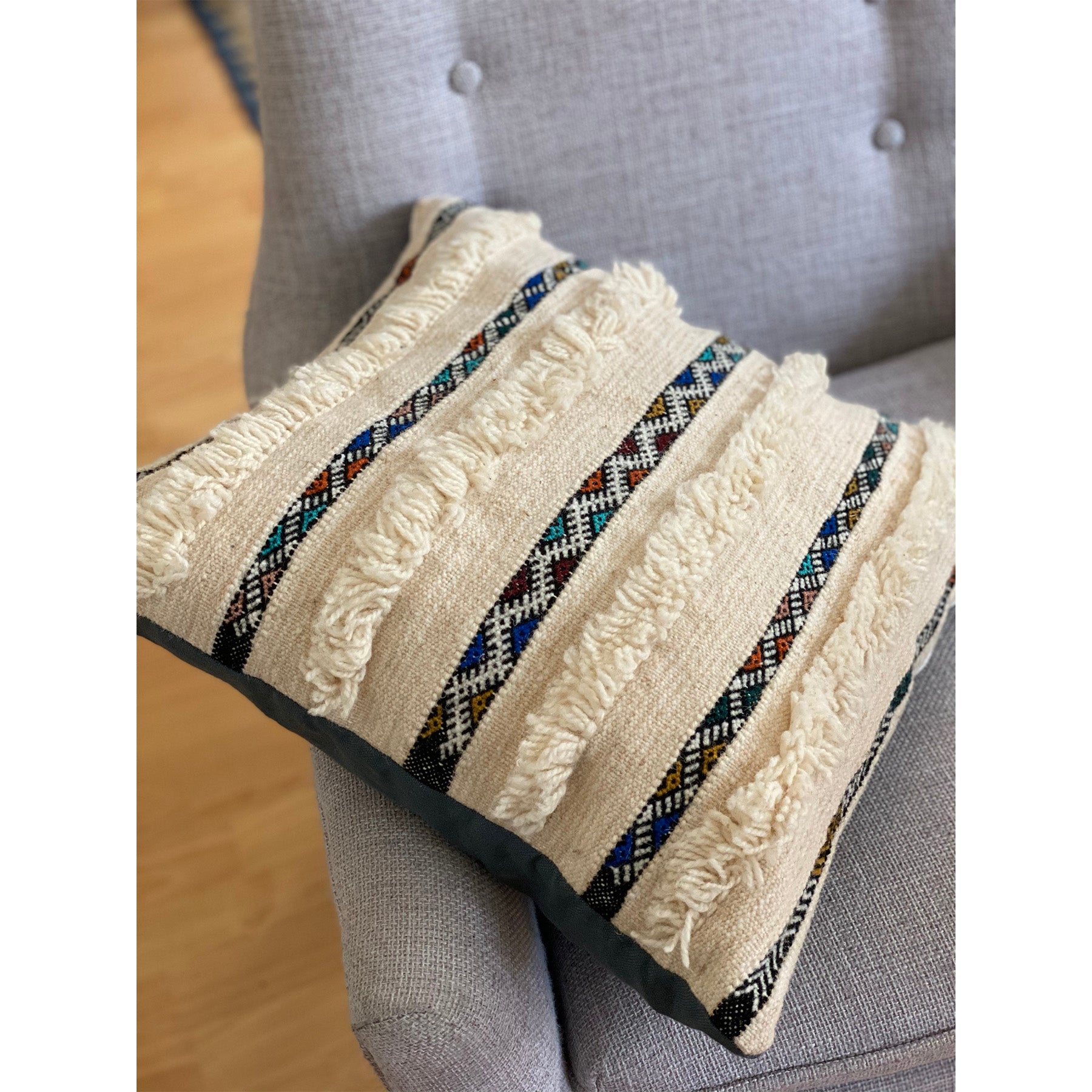 Colorful wedding blanket pillow with tufted bands interspersed with colorful geometric weaving