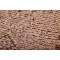 Detail of low-pile vintage Moroccan Berber rug with faded colors and classic design