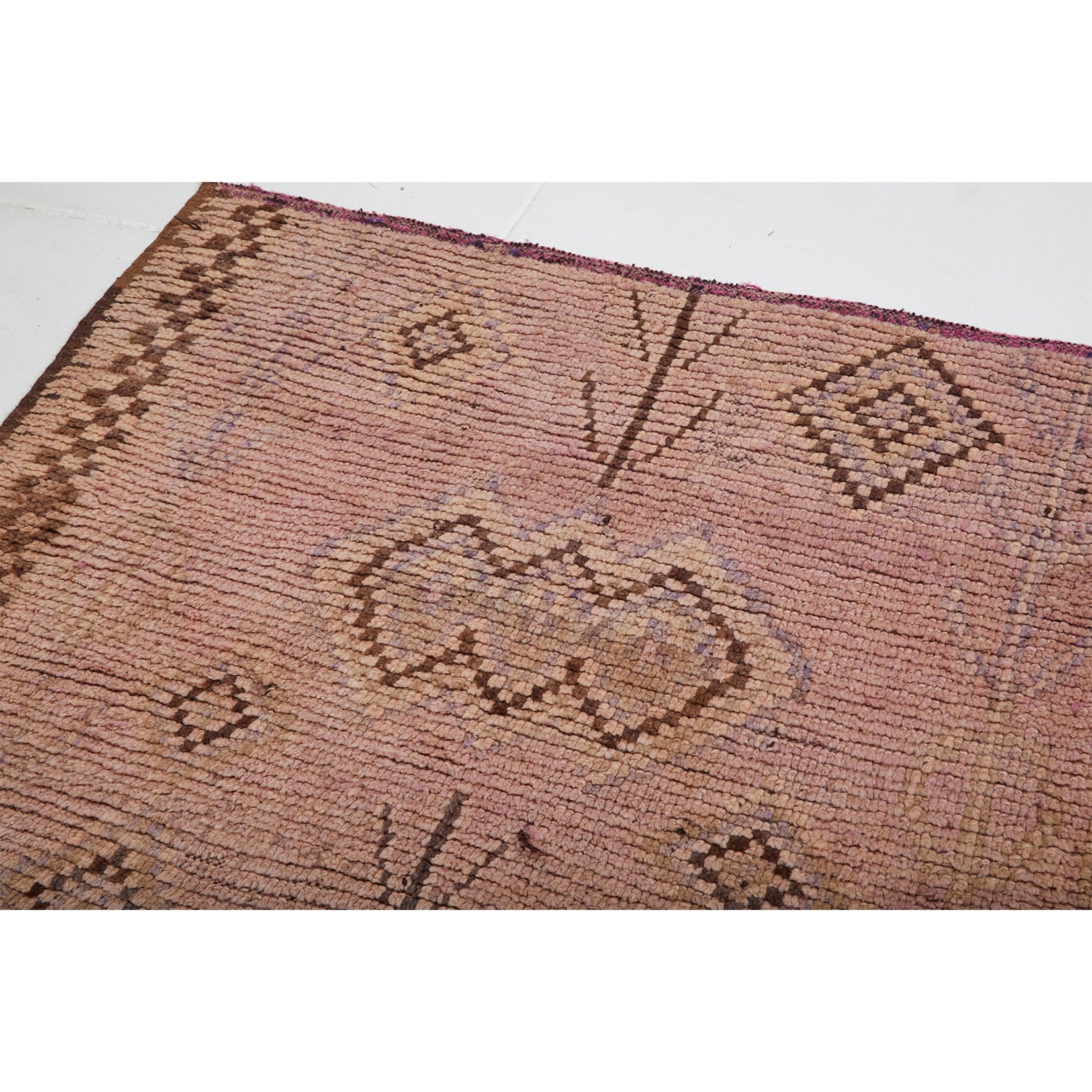 Detail of checkerboard vintage Moroccan rug with abstract diamond designs in brown and faded colors