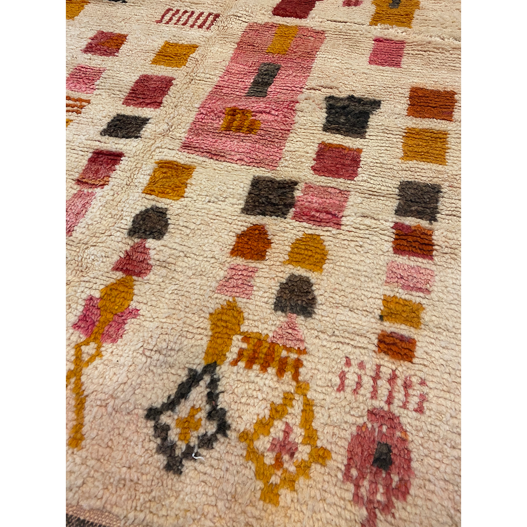 Detail of a modern Moroccan rug that would look best in a child's nursery with pink and mustard yellow designs