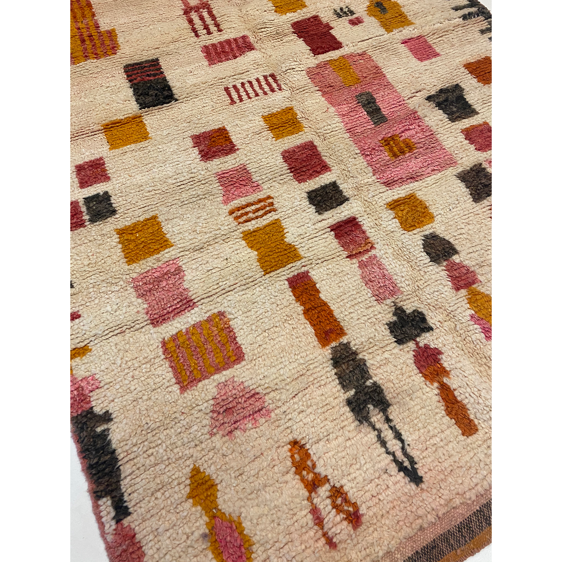 cream-colored Moroccan rug with designs in blush pink and mustard yellow