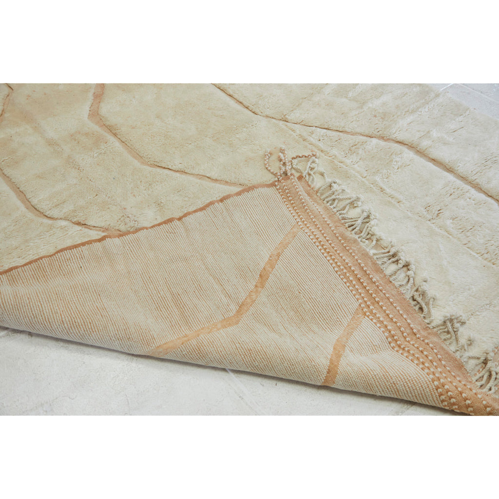 Detail of neutral Beni Mrirt rug where we see the backside of the rug flipped up and the weave detail