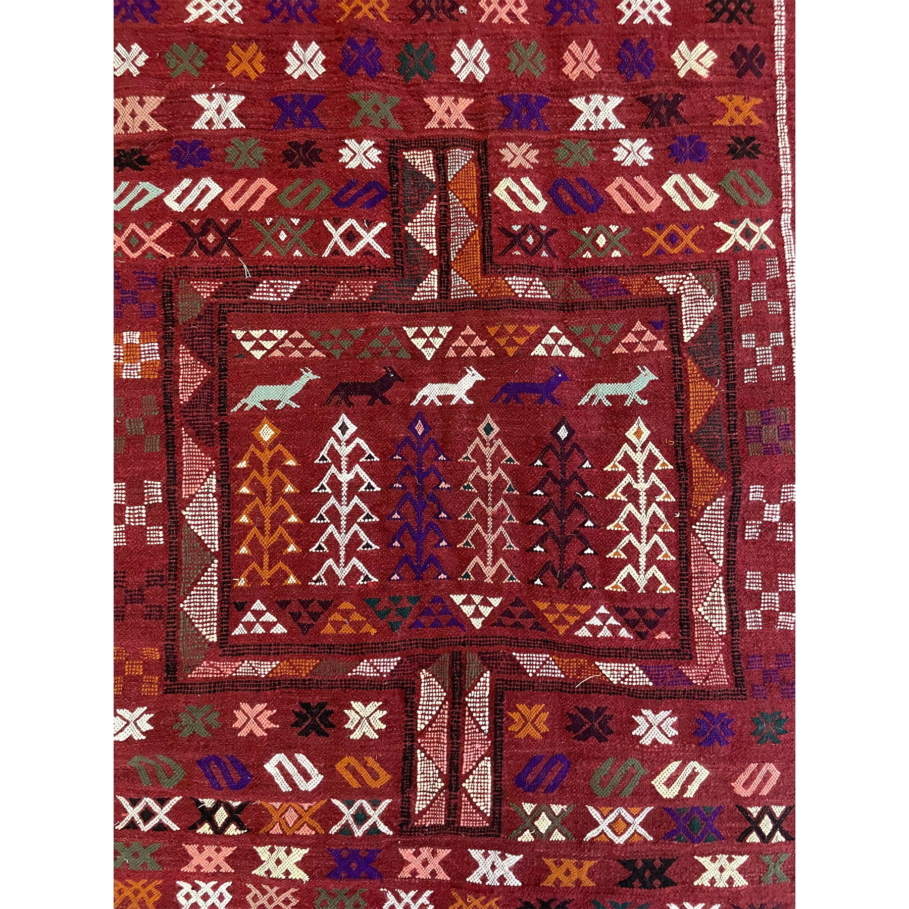 Traditional medium sized Moroccan rug in dark red color with details in purple, olive green, pink, and orange  | Kantara Moroccan Rugs in Los Angeles